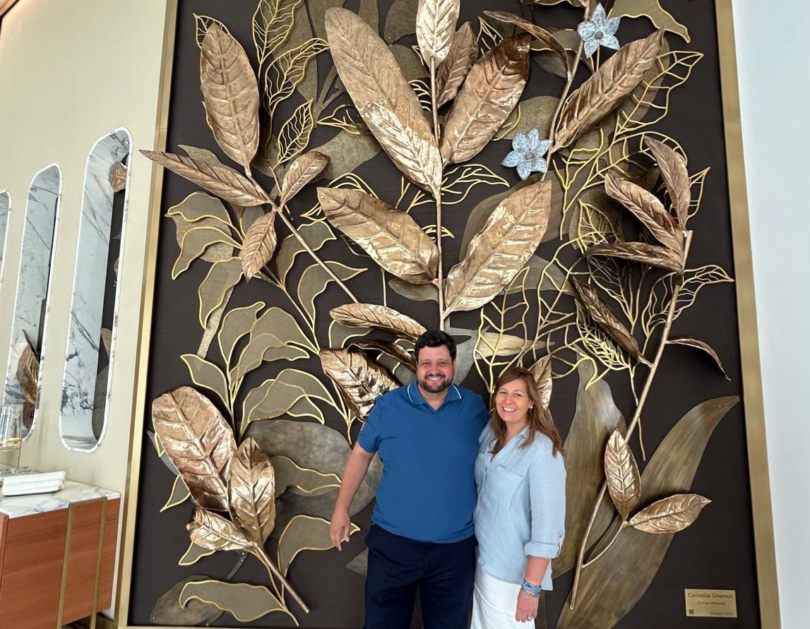 Manu Soriano y su mujer posan abrazados ante un gran mural decorativo de hojas doradas en ZEM Clinic