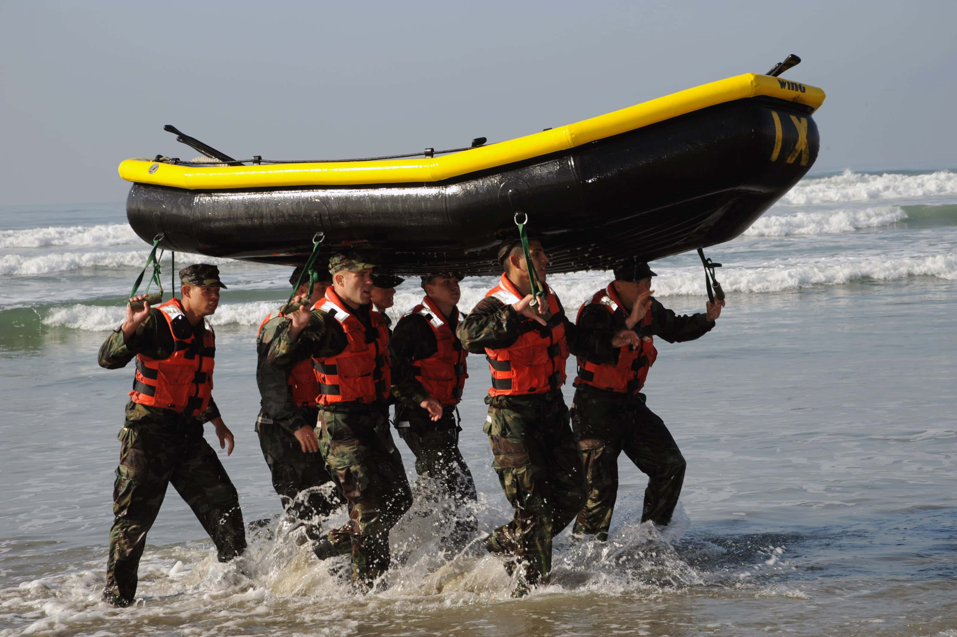 Equipo de Navy SEALs avanzando juntos por el agua durante un entrenamiento de cohesión