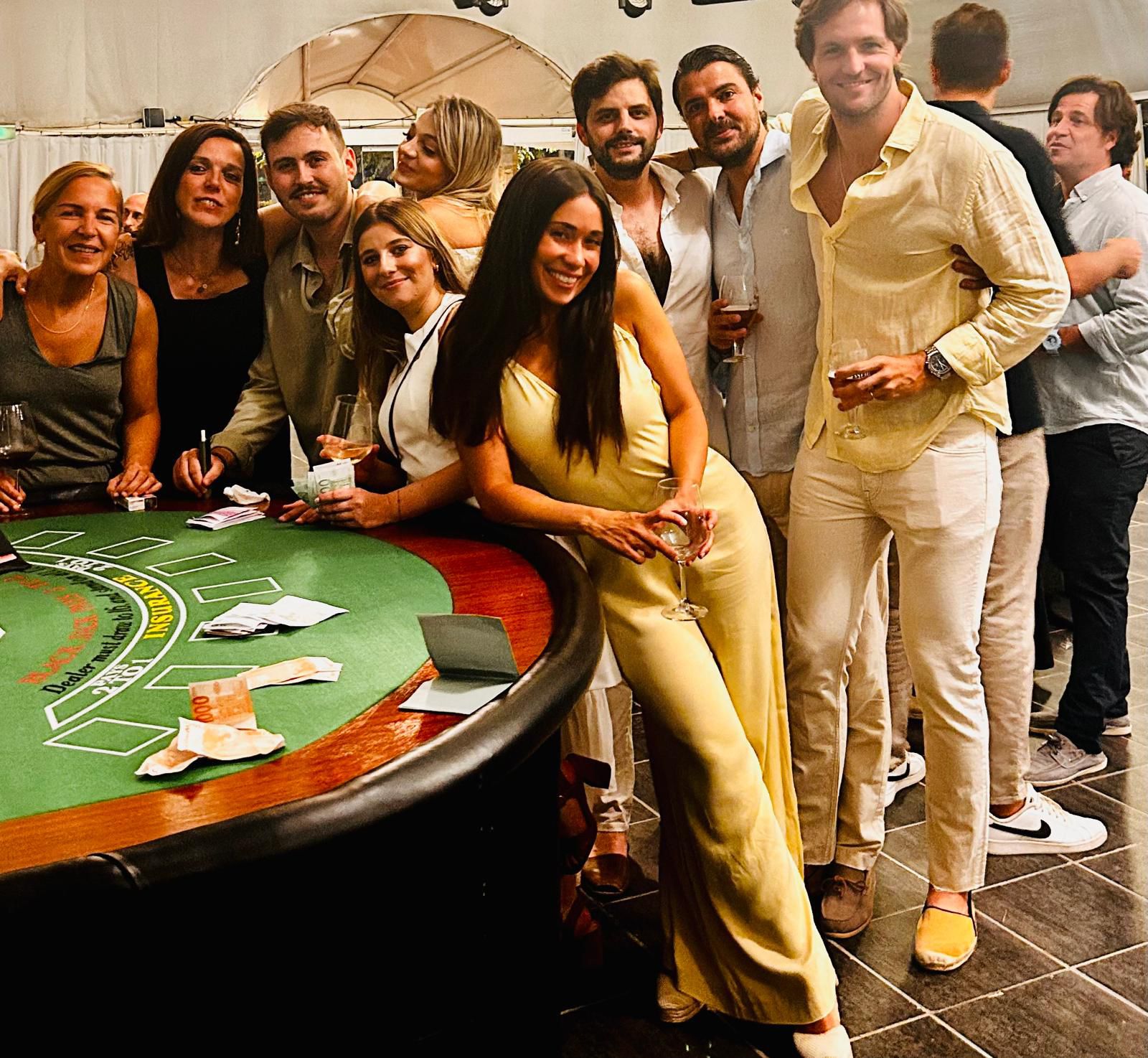 Compañeros del equipo posan sonrientes junto a una mesa de blackjack en la fiesta tipo casino