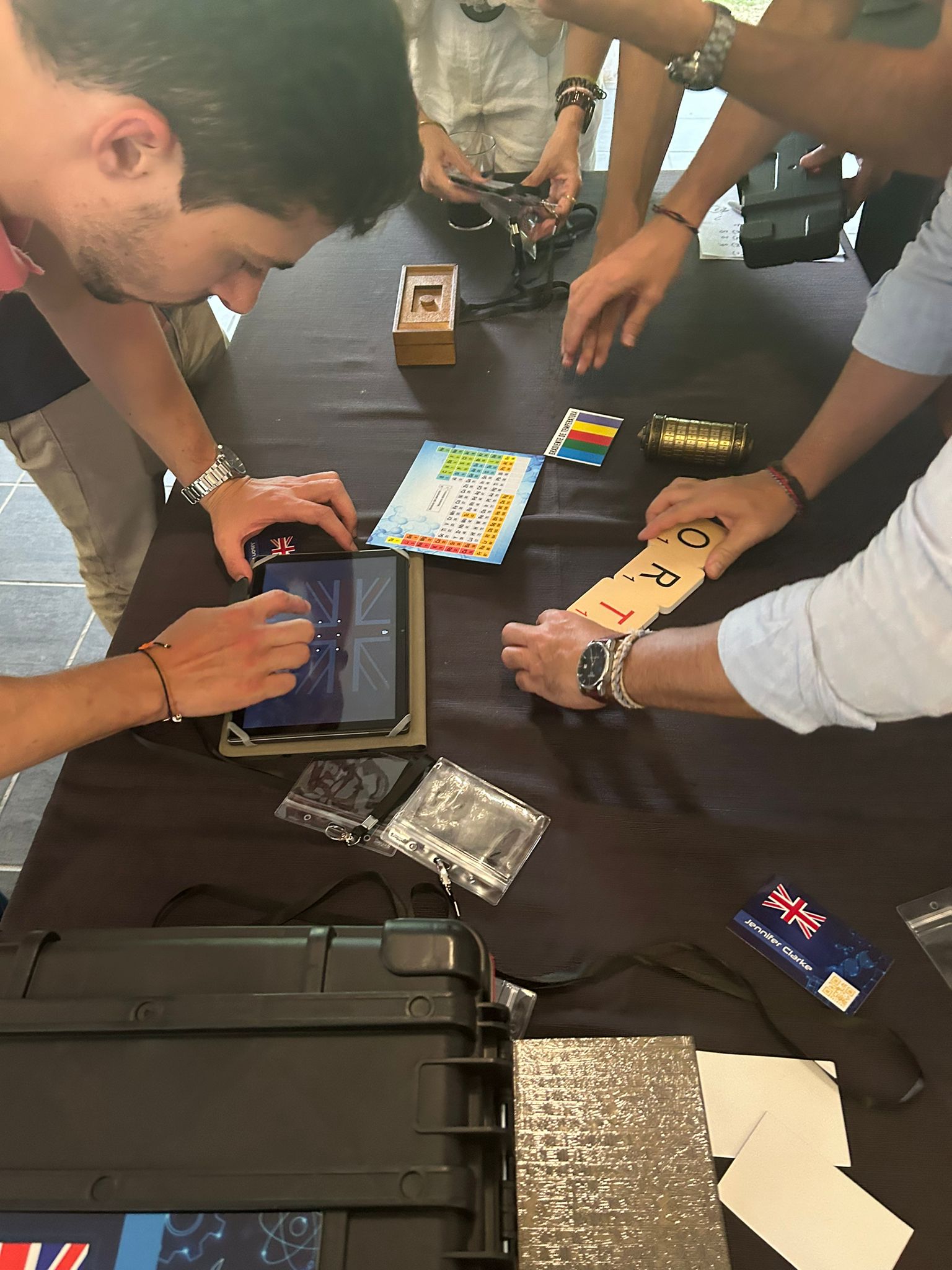 Equipo resolviendo un enigma con tablet, fichas y candados sobre una mesa durante el escape room