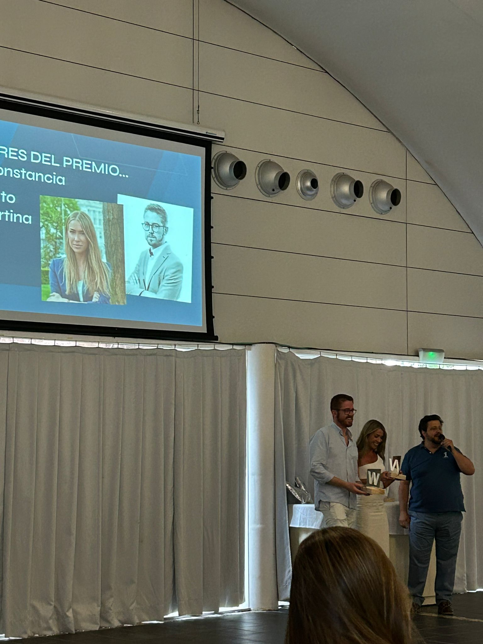 Manu Soriano entrega un premio W Award en el escenario mientras la pantalla muestra a los galardonados