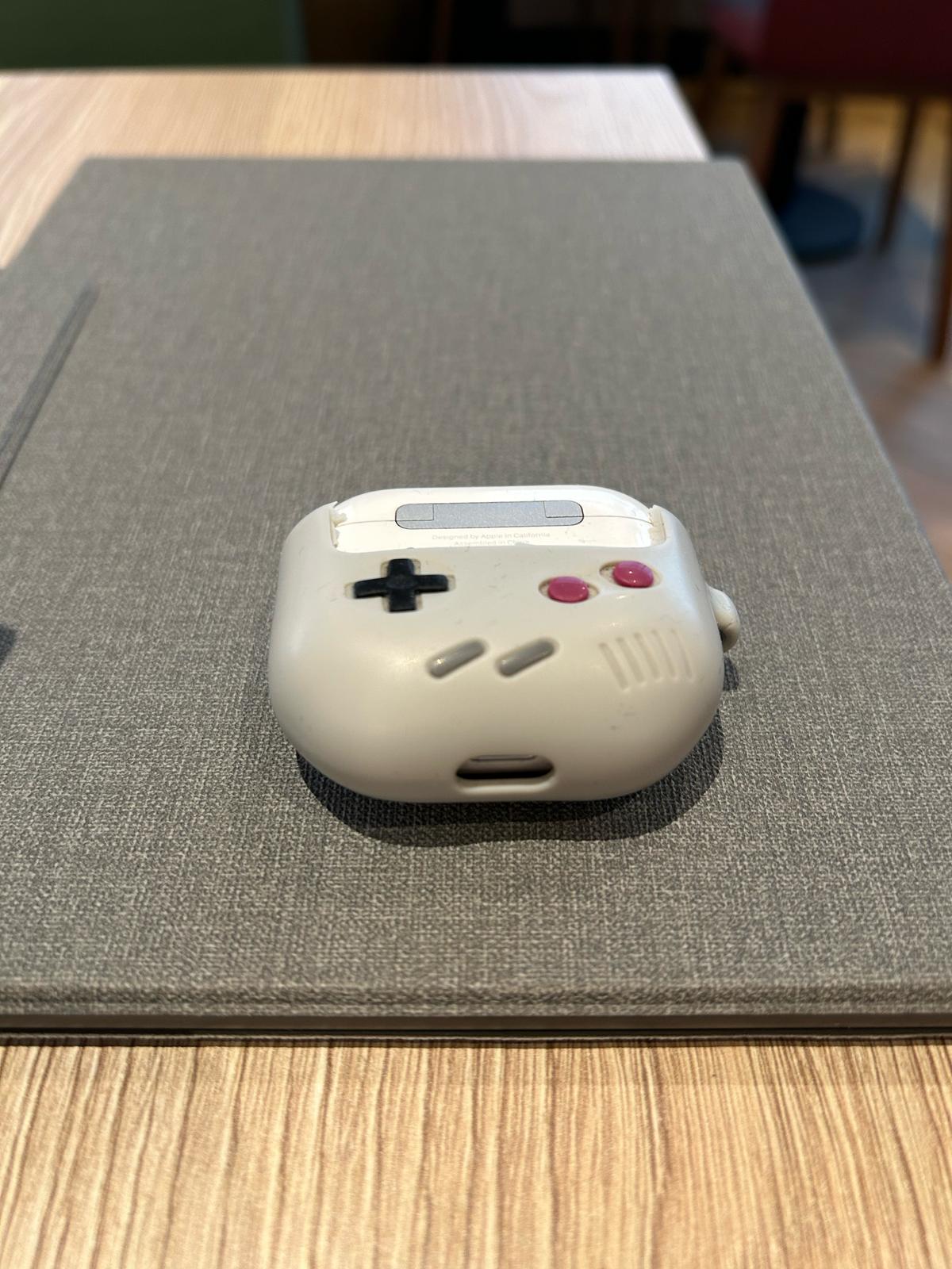 Funda con forma de mando de Game Boy clásico sobre una mesa de madera