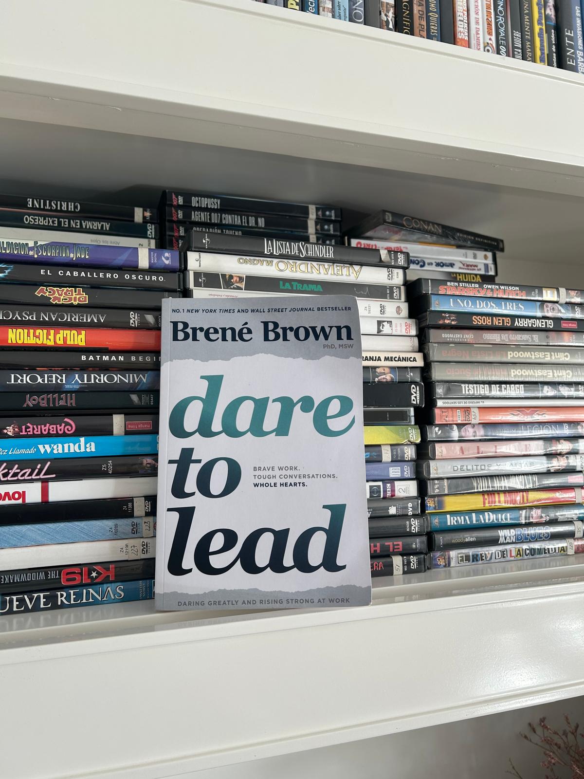 Libro Dare to Lead de Brené Brown apoyado en una estantería con películas en DVD