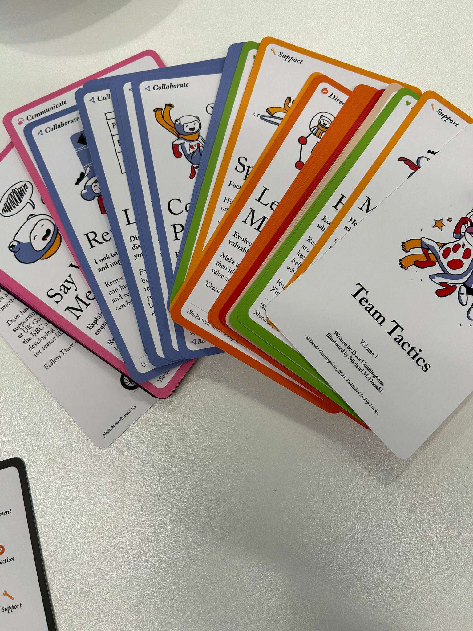 Cartas de colores de la baraja Team Tactics desplegadas en abanico sobre una mesa blanca