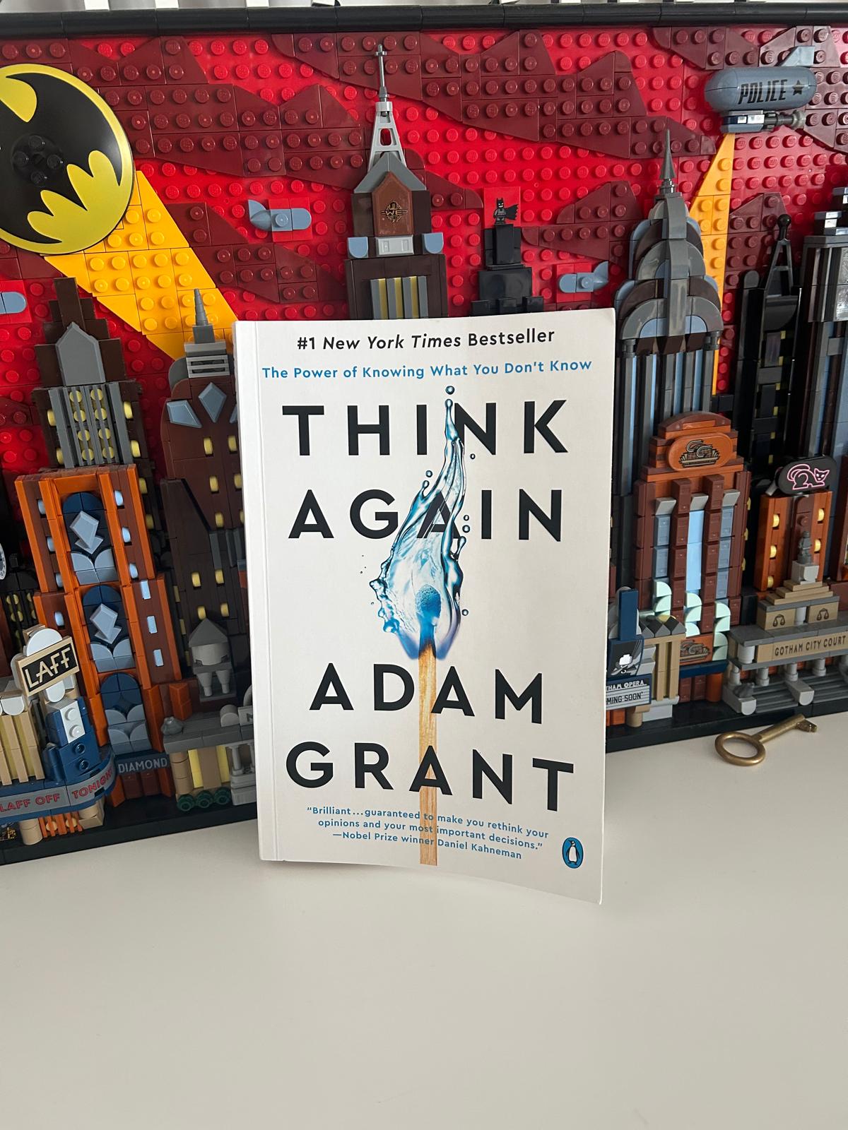Libro Think Again de Adam Grant frente a una maqueta de Lego de Gotham City con el logo de Batman