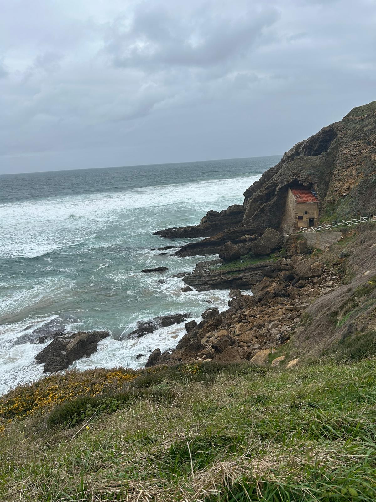 Ermita de Santa Justa encajada en un acantilado sobre el mar bravo de la costa de Cantabria