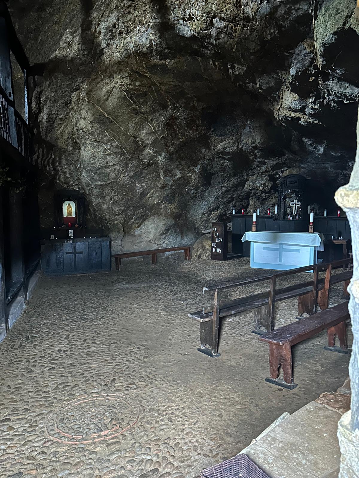 Interior excavado en roca de la ermita de Santa Justa con altar y bancos de madera