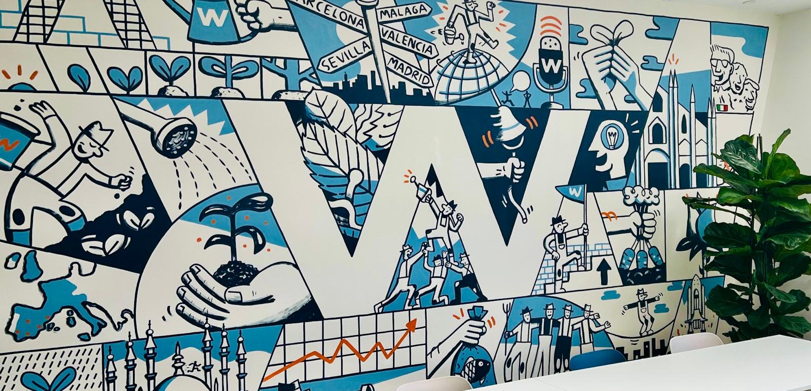 Mural azul y blanco en la oficina de W Executive con la W gigante y escenas de su historia