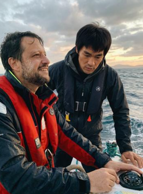 Dos hombres con chalecos salvavidas en una embarcacion al atardecer sobre el mar